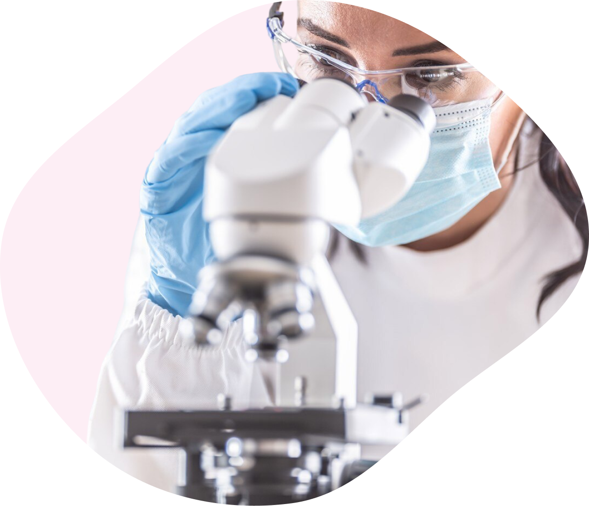 Person wearing protective gear using a microscope in a laboratory setting