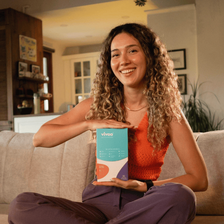 Woman sitting on a couch holding a Vivoo box in a living room.