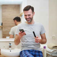 man looking at his phone while holding a Vivoo urine strip