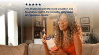 Woman holding a Vivoo Ovulation & Pregnancy Test in a living room setting.