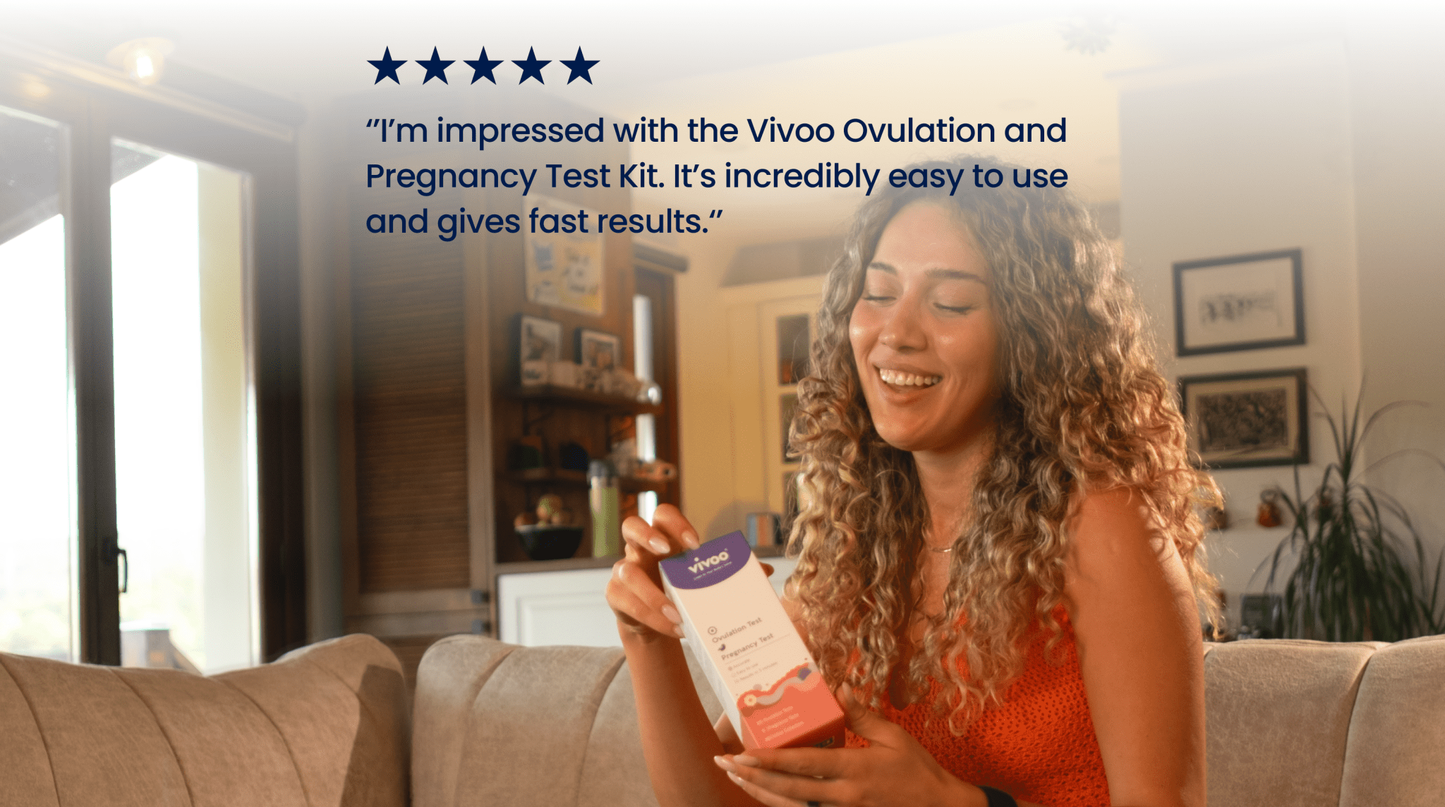 Woman holding a Vivoo Ovulation & Pregnancy Test in a living room setting.