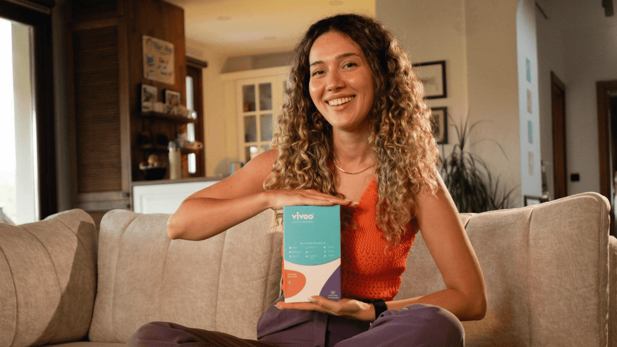 Woman holding a box labeled 'Vivoo' in a living room setting