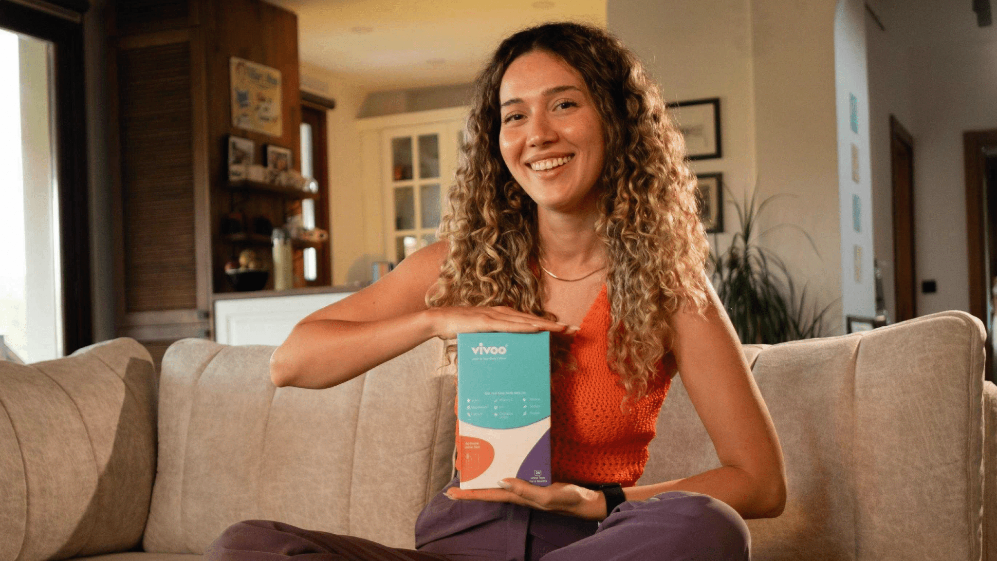 Woman holding a box labeled 'Vivoo' in a living room setting